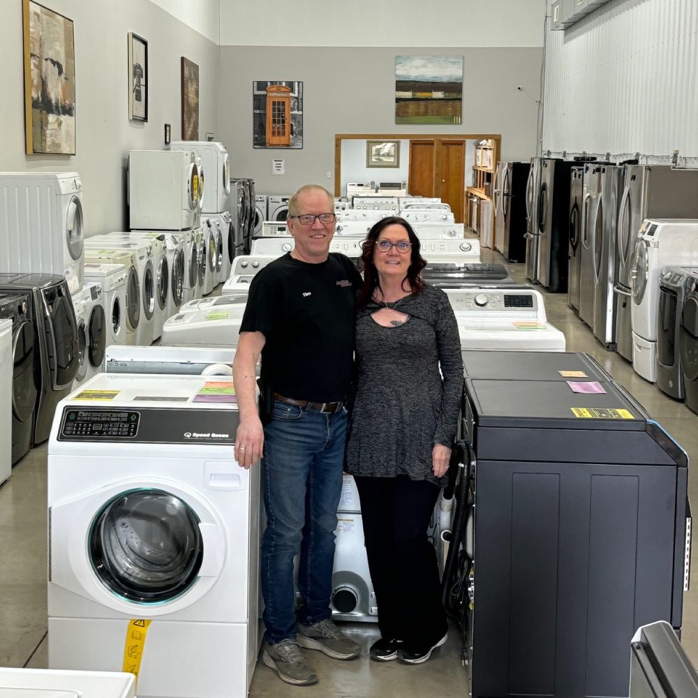 Appliance-Solutions-Ham-Lake-MN-Homepage-Owners-Image man and woman standing next to each other in their appliance showroom - Appliance Solutions