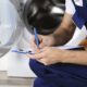 main crouching down near a washing machine with a pen and clipboard - Appliance Solutions appliance maintenance