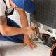 man wearing a blue hat and blue overalls fixing an appliance - Appliance Solutions appliance repair