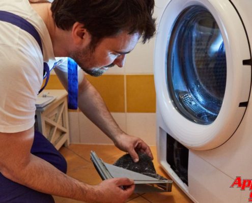 man wearing blue overalls fixing a white dryer - Appliance Solutions dryer repair