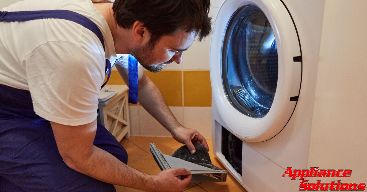 man wearing blue overalls fixing a white dryer - Appliance Solutions appliance maintenance