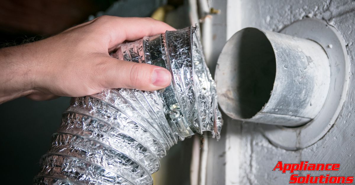 hand removing dryer vent from the machine - Appliance Solutions dryer repair