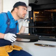 AppliancesSolutions-oven-repair-041520251 repair man sitting next to open oven - Appliance Solutions oven repair
