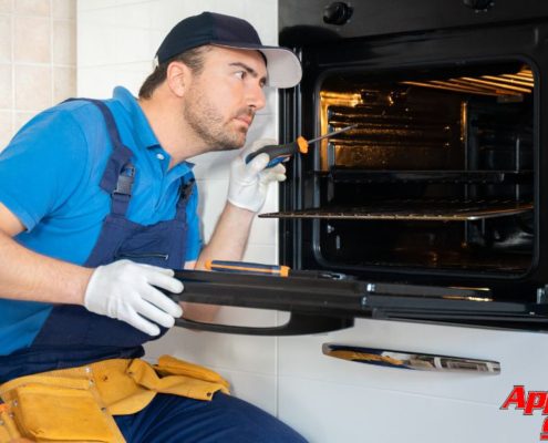 repair man sitting next to open oven - Appliance Solutions oven repair